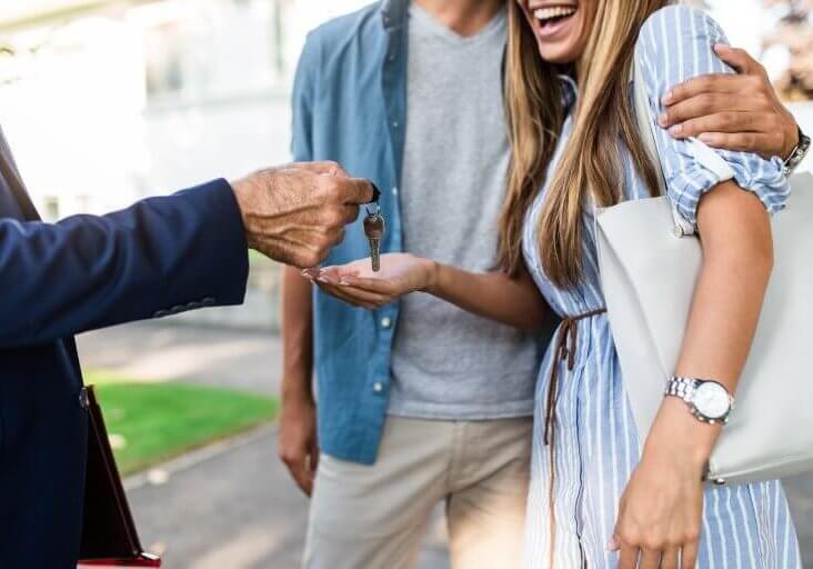 Young happy couple talking with real estate agent and buying a new house.