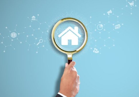 Property Management: Businessman Hand Holding a Magnifying Glass with Property Icon on Light Blue Background. Inspection, Efficiency, Tenant Relations.